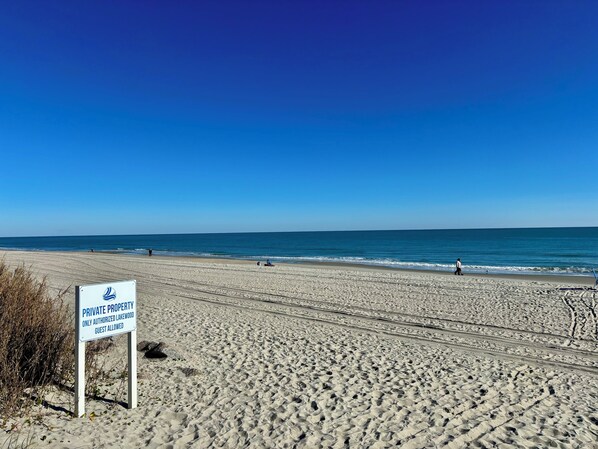 A beach with a sign indicating private property and guest access.