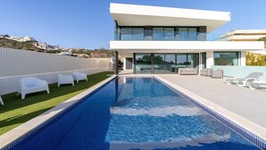 A modern house with a swimming pool, white outdoor furniture, and a clear blue sky. - Villa Marina - 33 by HelloVacations (Albufeira)