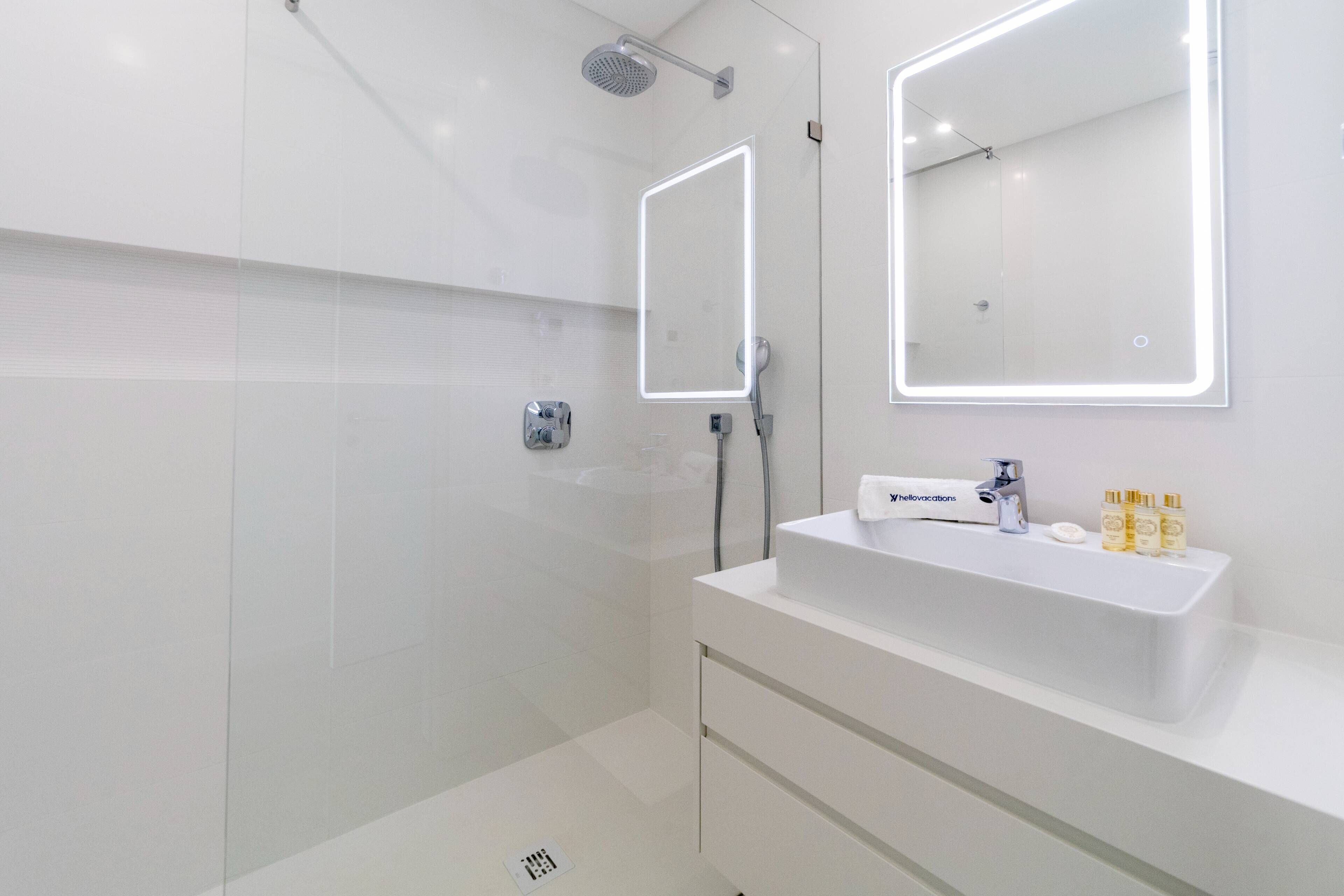 A modern bathroom with a white sink, two mirrors, and a shower.