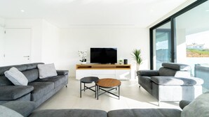 A modern living room with a grey sofa set, a wooden coffee table, and a flat-screen TV on a white console. - Villa Marina - 33 by HelloVacations (Albufeira)