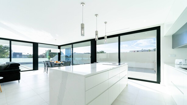 A modern kitchen with a large island, black chairs, and a dining table with chairs. - Villa Marina - 33 by HelloVacations (Albufeira)