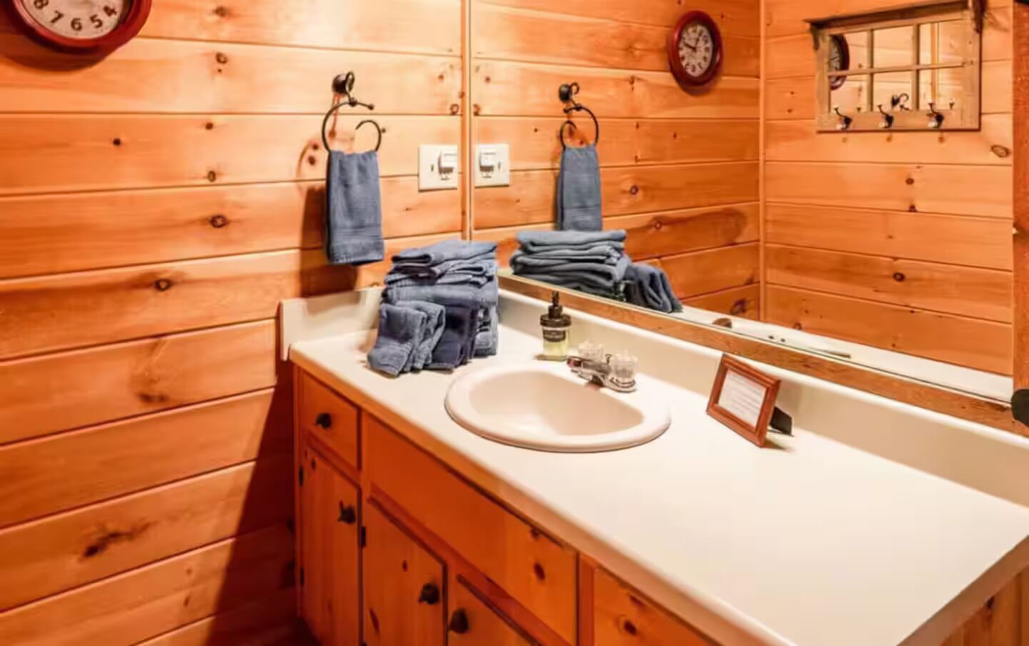 A wooden cabin-style bathroom with a white sink, wooden cabinets, and a mirror.