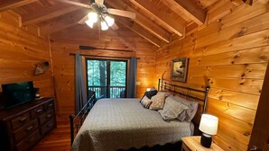 A cozy wooden cabin bedroom with a bed, dresser, and a ceiling fan. - Misty Lake Getaway - Hot Tub/Dog Friendly/EV Charger (Blue Ridge)