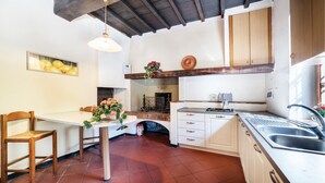 A kitchen with a white table, wooden chairs, a hanging light fixture, a stove, and a sink. - 6 bedroom amazing home in Dicomano (Dicomano)