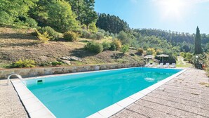 A rectangular swimming pool with a stone border, surrounded by a paved deck. - 6 bedroom amazing home in Dicomano (Dicomano)