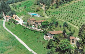 Una extensa propiedad con varias construcciones, una piscina y campos en terrazas.