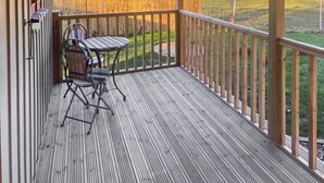 Una terraza de madera con mesa y sillas, con vistas a un campo cubierto de césped.