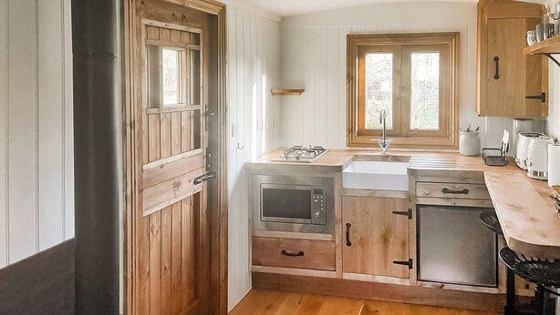 Una cocina con armarios de madera, estufa, microondas y lavamanos.