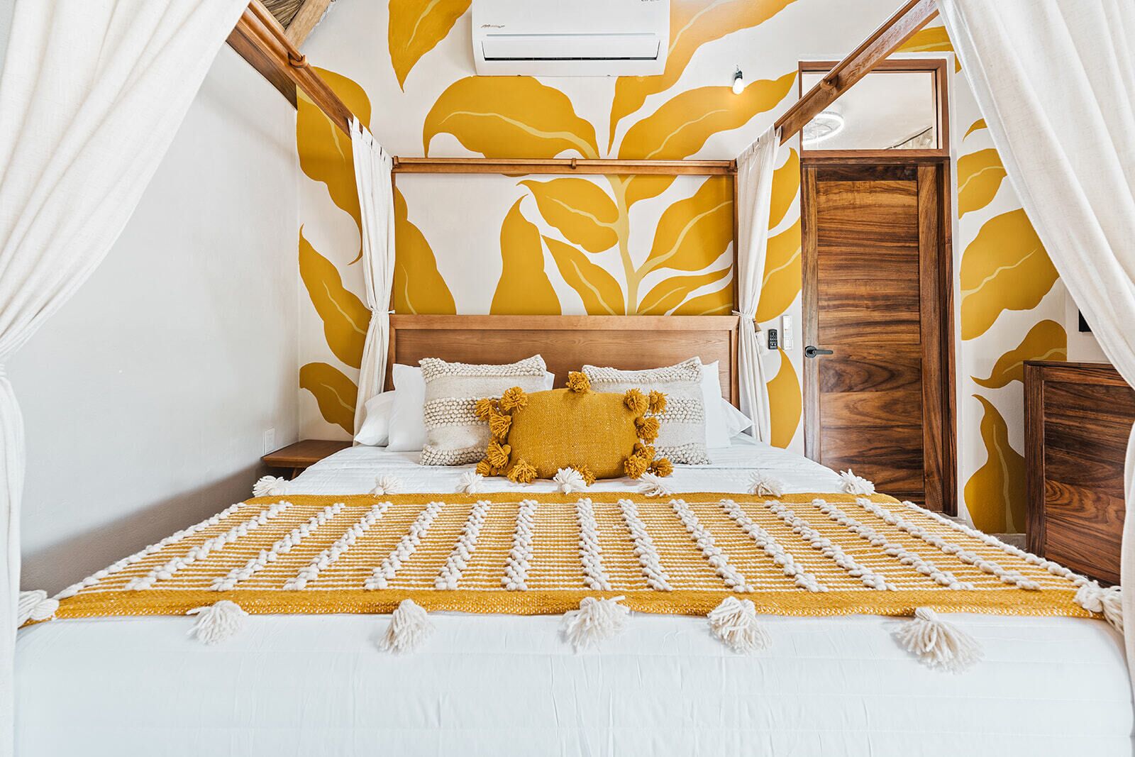 A bed with a yellow and white patterned bedspread, white pillows, and a wooden headboard.