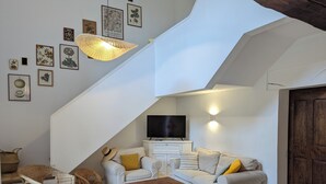 Uma sala de estar estilo loft com escada, móveis de vime, mesa de centro de madeira e televisão de tela plana.
