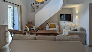 Uma sala de estar ampla com teto alto, escada, sofá, mesa de centro de madeira e televisão.