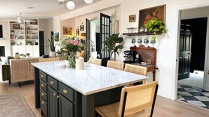 A modern kitchen with a marble island, dark cabinetry, and a coffee machine. - Designer Luxury Cottage with Saltwater Pool on Private 4 Acres (Johnson City)