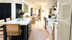 A modern kitchen with a central island, wooden chairs, and a dining table. - Designer Luxury Cottage with Saltwater Pool on Private 4 Acres (Johnson City)