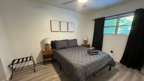 A bedroom with a bed, two bedside tables, a ceiling fan, and a window with curtains. - Location Lake Eola View 1 Bedroom condo (Orlando)