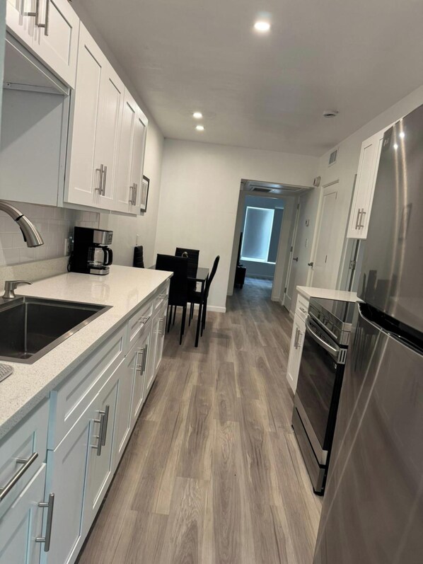 Una cocina moderna con armarios blancos, electrodomésticos de acero inoxidable y suelo de madera.