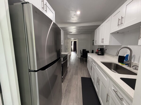 A modern kitchen with stainless steel appliances, white cabinetry, and a black countertop.