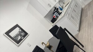 A modern kitchen with white cabinets, a black dining table, and a black chair.