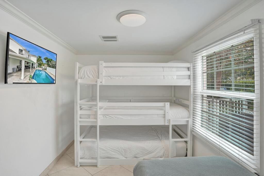 Een slaapkamer met stapelbed, een raam en een ingelijste foto aan de muur.