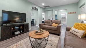A modern living room with a flat-screen TV, leather sofas, a coffee table, and a dining area in the background. - Closest to Springville Ranch & Gateway to the Sequoias•Pet Friendly•Sleeps 10 (Springville)