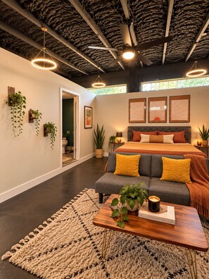 A modern bedroom with a bed, a sofa, and a coffee table with a book and a candle.