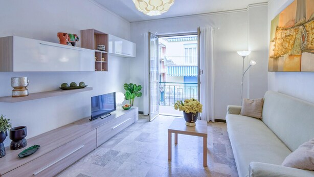 Ein modernes Wohnzimmer mit einem Flachbildfernseher, einem Holztisch und einer Couch. Auf dem Tisch steht ein Blumentopf und eine Regal mit Dekoration.