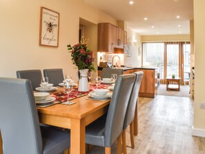A dining area with a wooden table set for four, surrounded by chairs. - 3 bedroom accommodation in Carnforth (Carnforth)