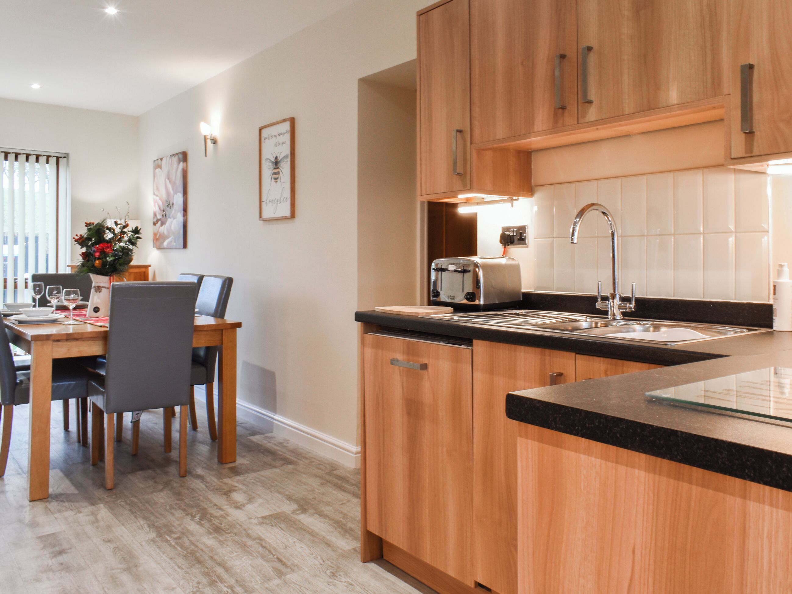 A modern kitchen with wooden cabinets, a black countertop, and a stainless steel toaster.