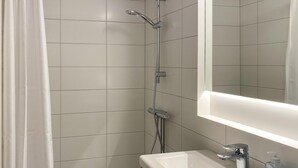 Une salle de bain avec une douche, un lavabo et un miroir.