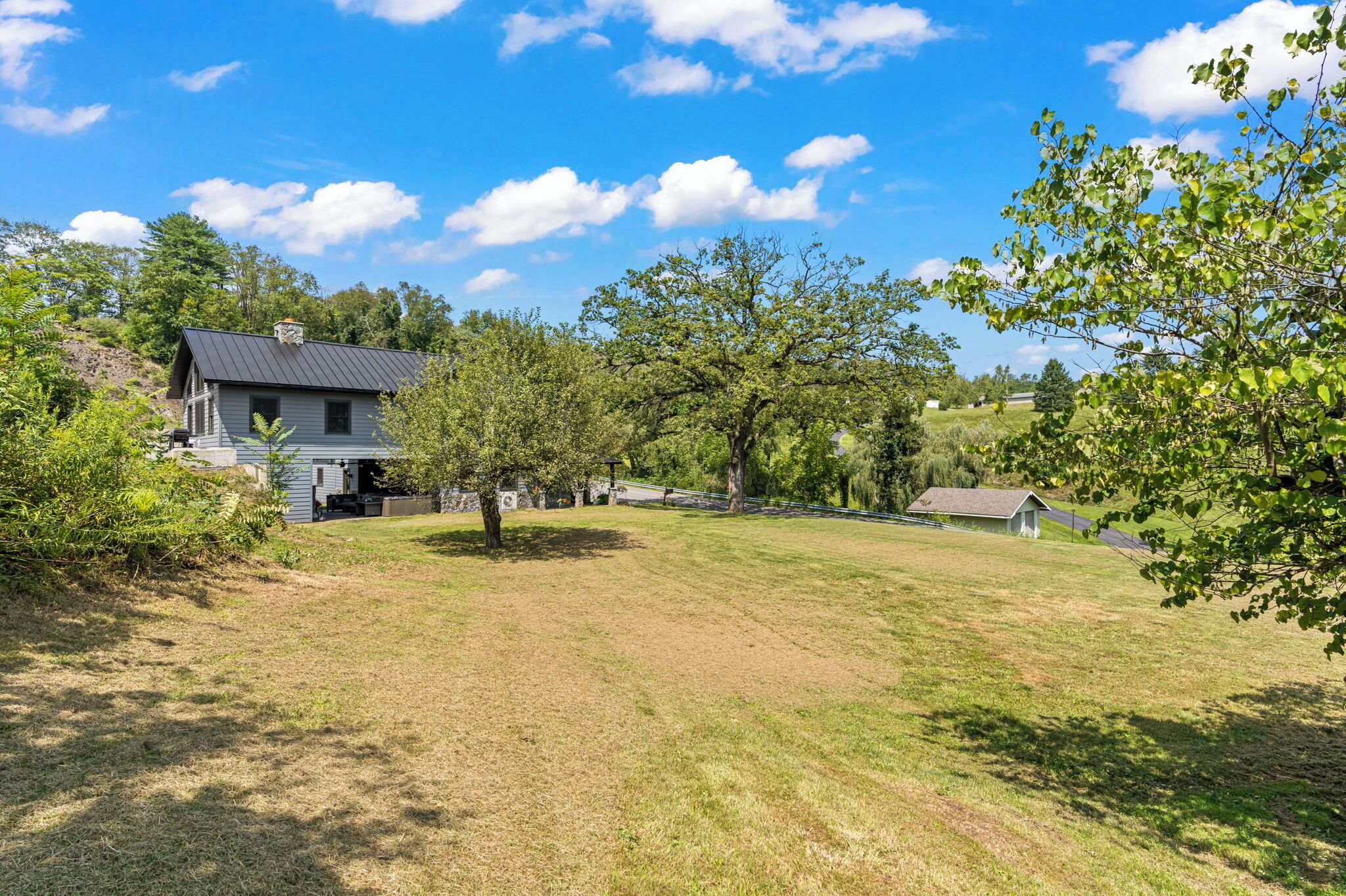 A house with a dark roof, surrounded by a grassy yard and trees.