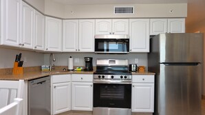 A modern kitchen with white cabinets, a stainless steel refrigerator, a built-in oven, a microwave, and a dishwasher. - Casa Playa #403 Beach Front - Dolphin Watch (Fort Myers Beach)