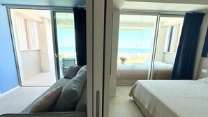 Et værelse med seng, sofa og balkon med udsigt over stranden.
