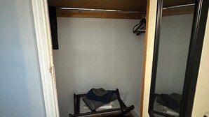 A compact room with a wooden bunk bed, a small shelf, and a door with a brass handle. - Charming 2-bedroom apartment in wonderful Queens with WiFi and Parking (Queens)