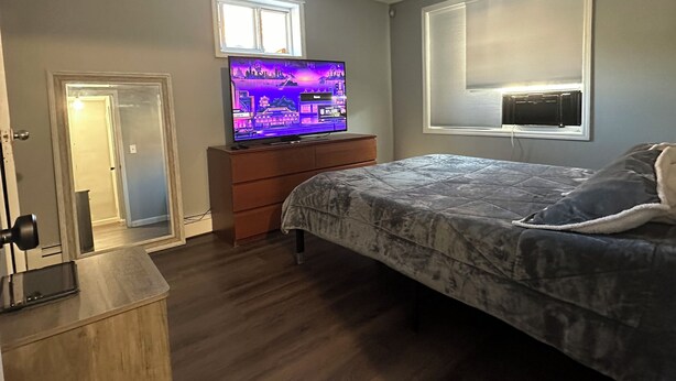 A bedroom with a bed, a TV, a dresser, and a door. - Charming 2-bedroom apartment in wonderful Queens with WiFi and Parking (Queens)