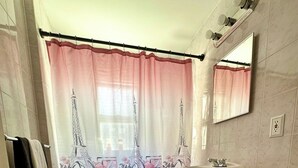 A bathroom with a toilet, sink, and shower curtain featuring the Eiffel Tower. - Charming 2-bedroom apartment in wonderful Queens with WiFi and Parking (Queens)