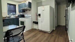 A compact kitchen with a dining area, a refrigerator, and a microwave. - Charming 2-bedroom apartment in wonderful Queens with WiFi and Parking (Queens)