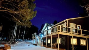 A two-story house with a balcony, surrounded by trees and snow. - Pikes Peak Views & Hot Tub | Mountain Home (Woodland Park)