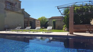 Una piscina con sillas de descanso y una pérgola.