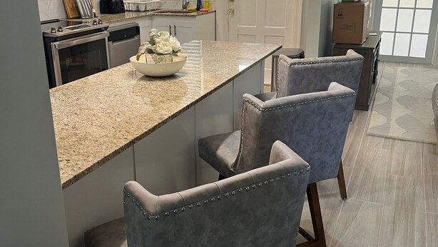Una cocina moderna con encimeras de granito, electrodomésticos de acero inoxidable y una isla central con taburetes de bar.