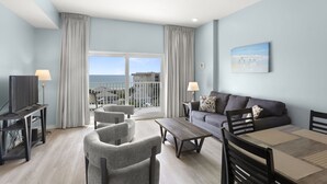 A modern living room with a balcony, a television, a sofa, and a dining table. - Ocean Sunset View, Steps to Beach (Madeira Beach)