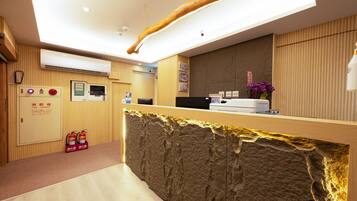 A reception desk with a wooden counter, a fire extinguisher, and a wall-mounted air conditioning unit.