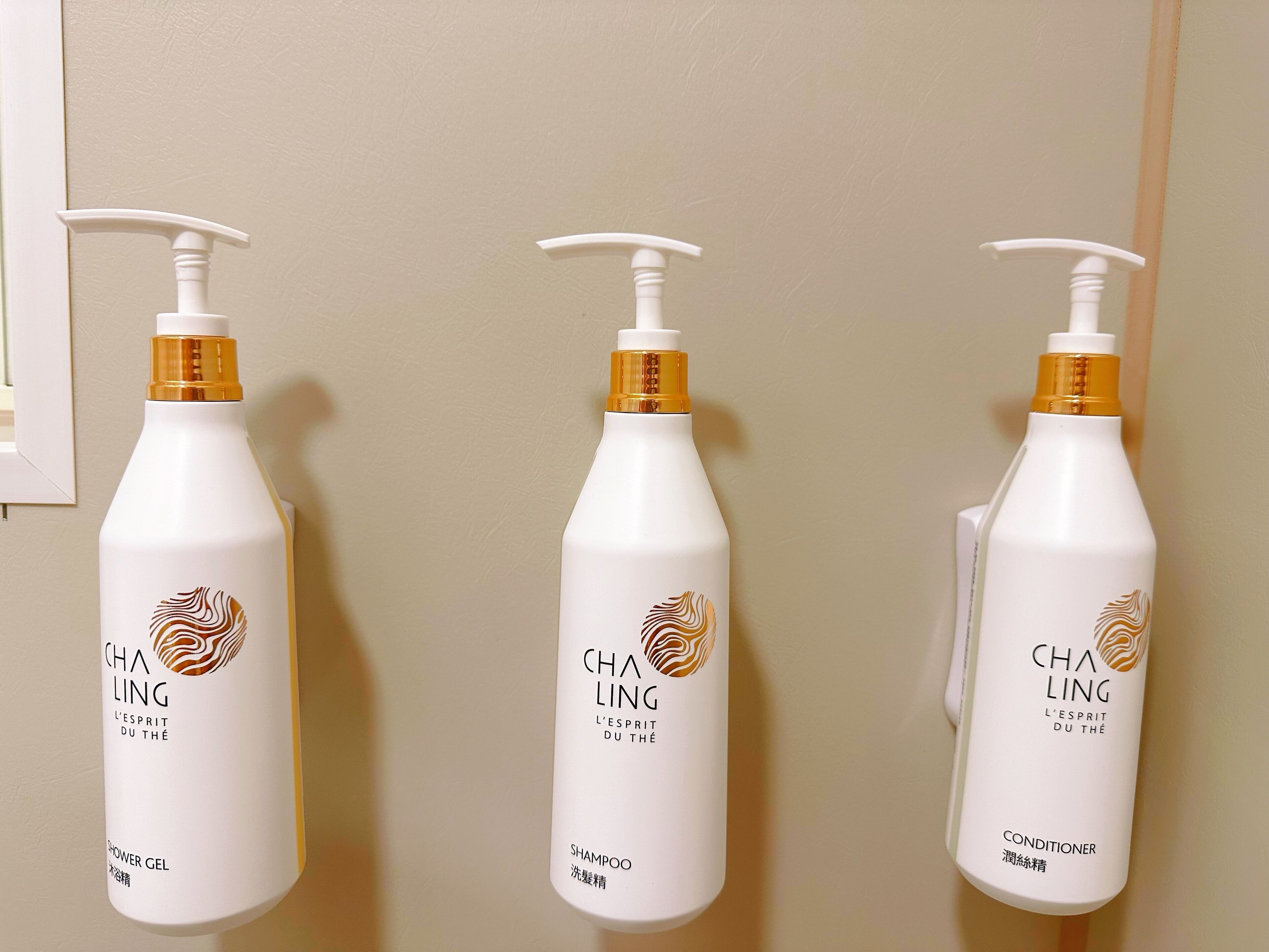Three bottles of Cha Ling shampoo and conditioner on a wall.