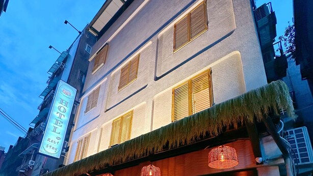 Un hôtel à la façade traditionnelle, doté de grandes fenêtres et d’une entrée bien visible, avec une porte en verre.