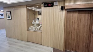 Une pièce comprenant un meuble en bois, une vitrine contenant divers objets et un thermomètre numérique fixé au mur.