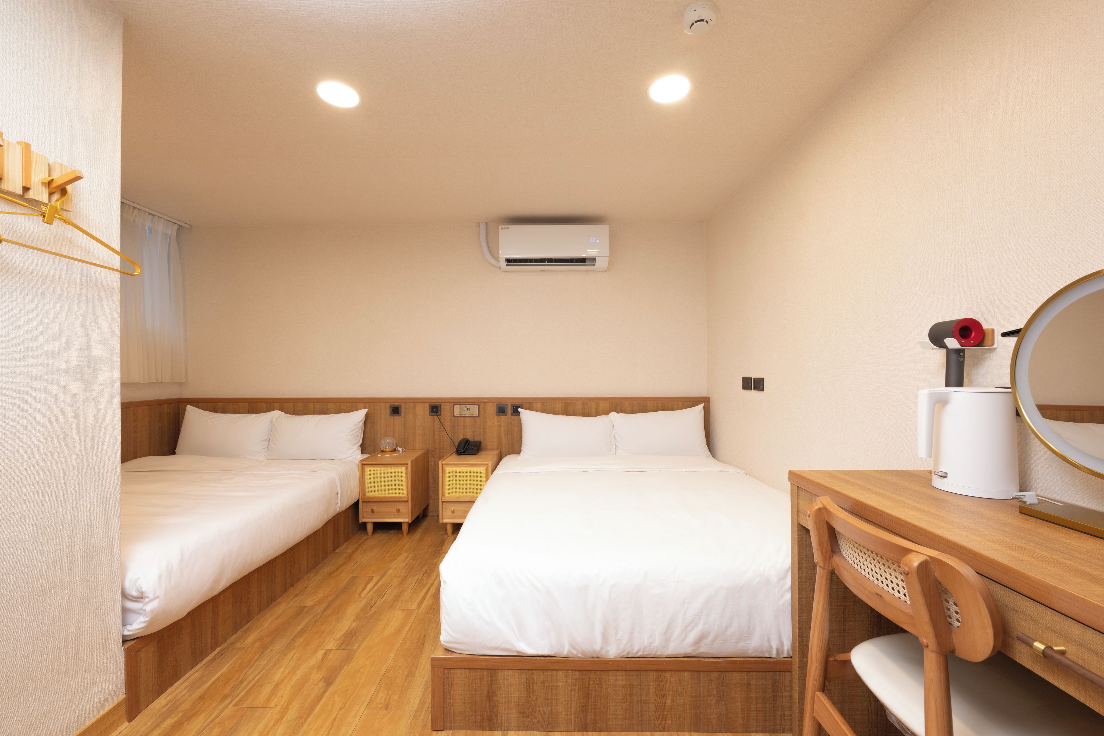 Ein Hotelzimmer mit zwei Betten, einem Holzschrank, einem Spiegel und einer Klimaanlage.