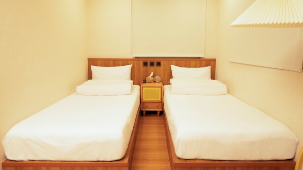 A twin room with two single beds, a wooden headboard, a bedside table, and a hanging lamp.