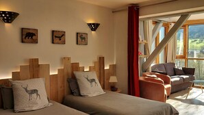 A cozy room with a bed, two sofas, and a window with a view of greenery.