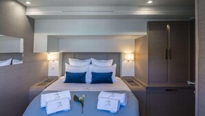 A modern hotel room with a large bed, two bedside tables, a wardrobe, and a mirror. - MUST SELL 1-3 wks ALL INCLUSIVE crewed BVI private yacht charter FP 67 Catamaran (Tortola)