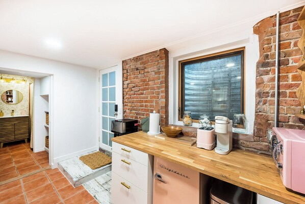 Una cocina con encimera de madera, pared de ladrillo y una ventana.