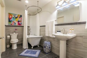 A bathroom with a toilet, a bathtub, a sink, and a mirror. - Perfect blend of style and serenity in this 3-br, 2-bath bungalow guest house.  (San Angelo)