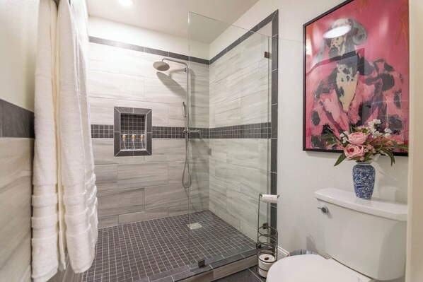 A modern bathroom with a glass shower enclosure, a toilet, and a sink.